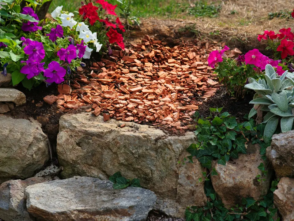 A planting bed with decorative mulch, natural stone edging and flowering borders