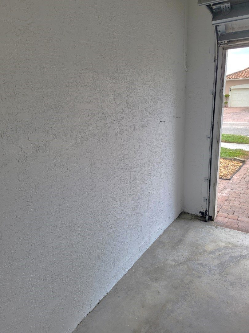 Garage interior wall after painting, with the door open to a paver driveway